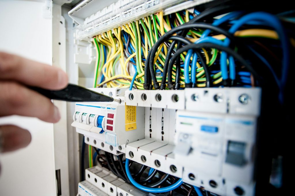 pexels photo 257736 257736 Hand of electrician working on a circuit breaker panel with colorful wires, ensuring safe electrical connections.