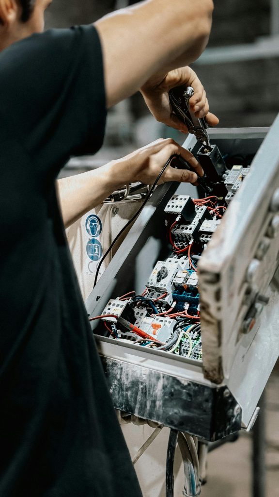 pexels photo 33694019 33694019 Technician adjusting wires in an electrical control panel for maintenance